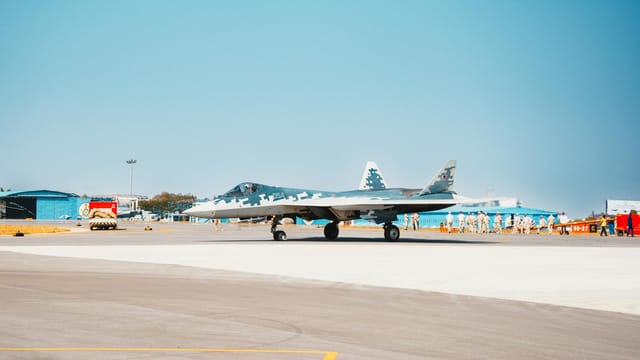 A Sukhoi Su-57 fighter jet stationed on a military airfield runway.