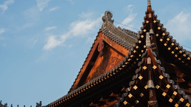 Detailed view of a traditional Chinese temple roof under a clear blue sky.