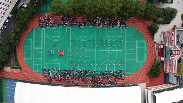 Aerial view of a sports complex in Shanghai with people gathered on a green field.