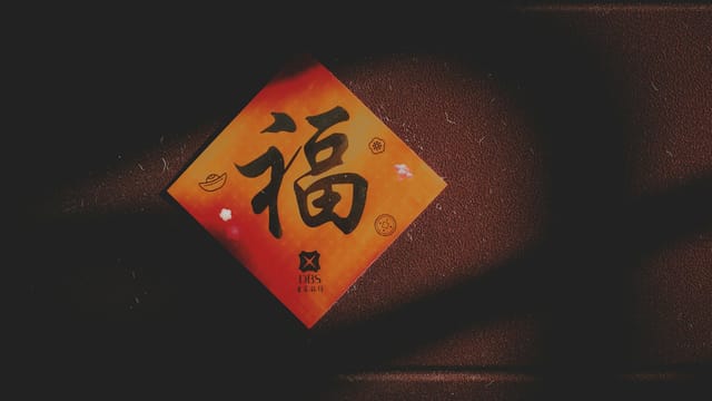 Close-up of a Chinese character card on a textured brown wall with shadows.