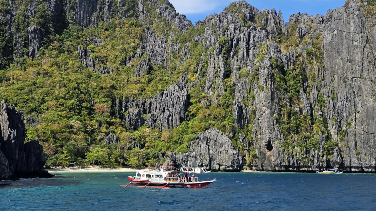 Enjoy a breathtaking view of boats by the limestone cliffs of El Nido, Philippines.