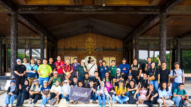 A diverse group of adults and children posing in front of an ornate cultural building entrance.
