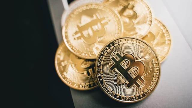 Close-up of golden Bitcoin coins on a laptop keyboard, symbolizing cryptocurrency investment.