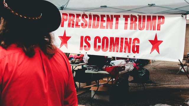 Banner promoting a political event for Donald Trump in Wheeling, WV with market stalls.