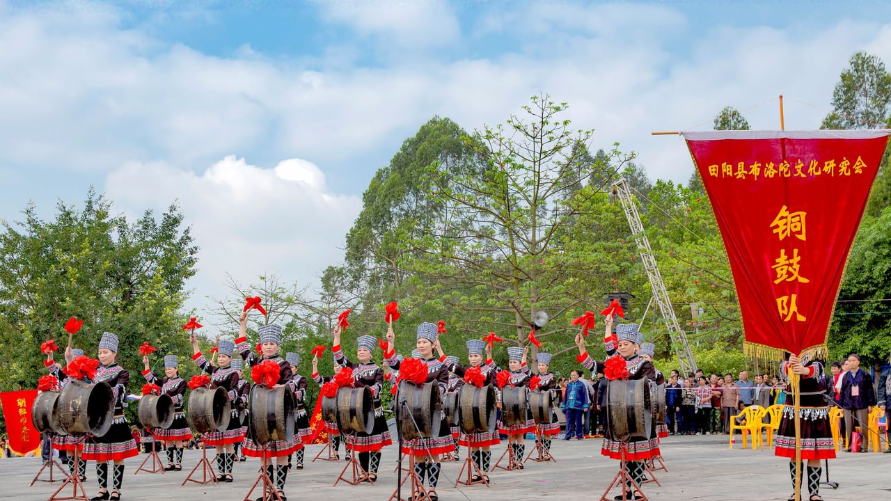 Cultural drum performance outdoors in Guangxi, China, showcasing traditional attire.