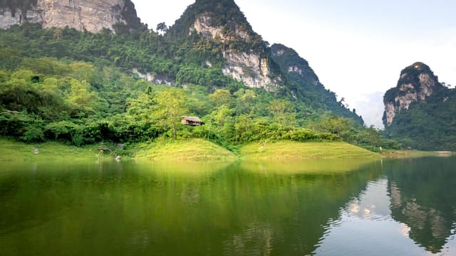 Amazing landscape of calm Na Hang lake surrounded by huge rocky mountains covered with green trees on sunny day in Tuyen Quang province