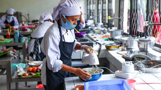 Culinary students in Indonesia learn food preparation techniques in a professional kitchen.