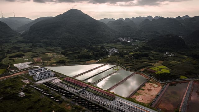 A breathtaking aerial shot of agricultural fields with ponds and rolling hills.