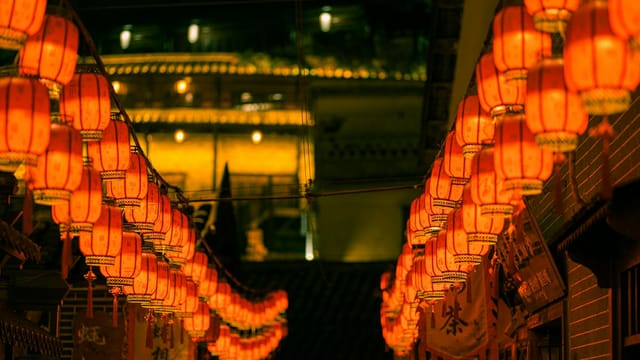 Illuminated red Chinese lanterns line a vibrant street in Shenzhen, China at night.