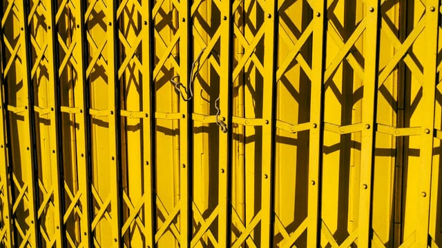 Vivid yellow metal gate with geometric patterns casting shadows.