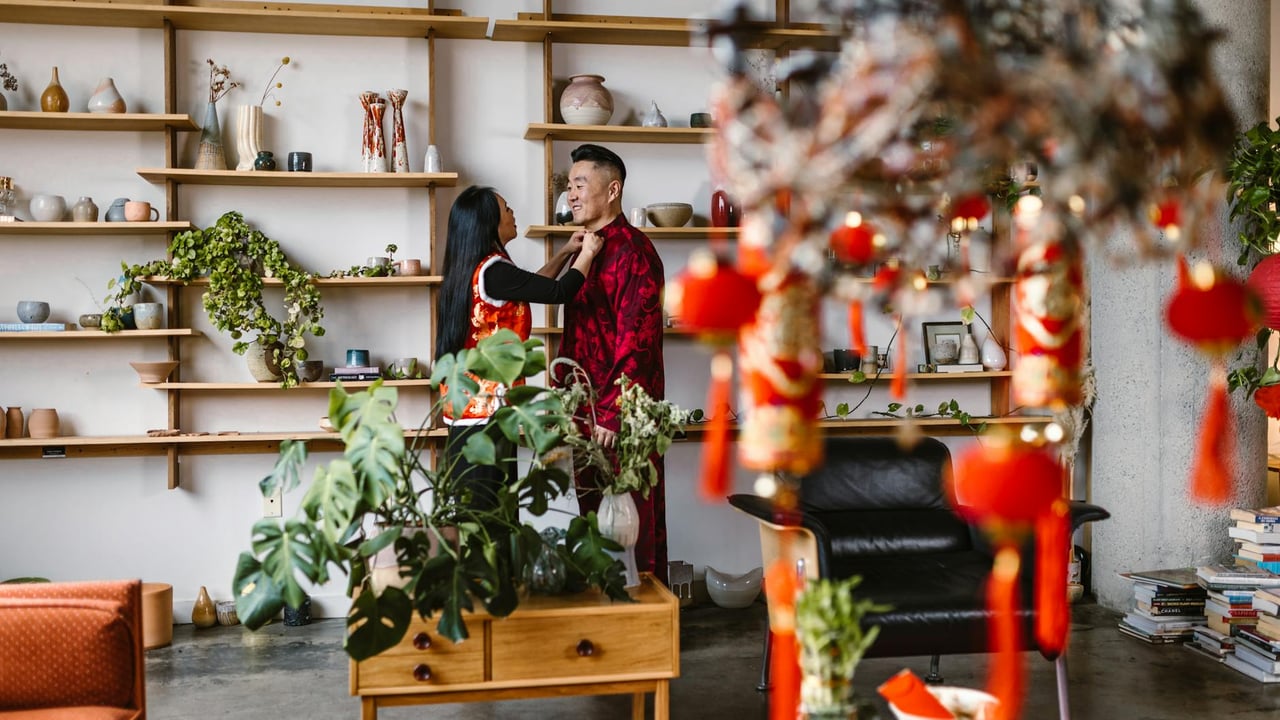 A couple celebrating Chinese New Year in a beautifully decorated room with traditional red ornaments.