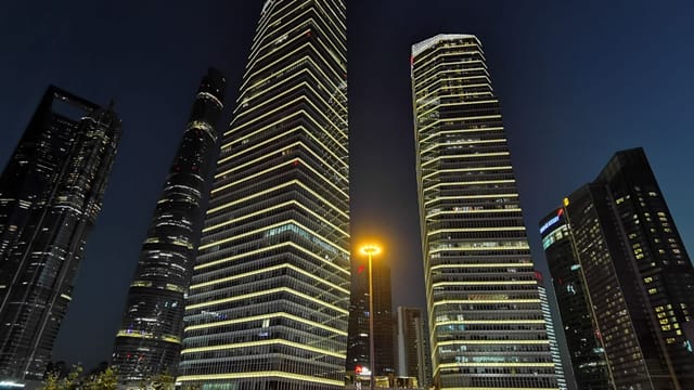 Night view of Shanghai's illuminated skyscrapers showcasing modern urban architecture.