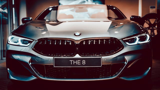 Close-up frontal view of a sleek silver BMW 8 Series convertible displayed in a showroom.