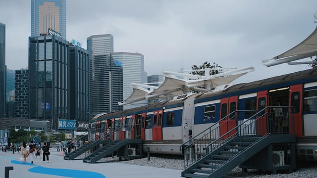 Urban train platform with skyscrapers in Hong Kong skyline.