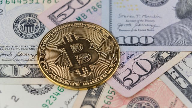 Close-up of a Bitcoin coin on US dollar banknotes, symbolizing cryptocurrency and traditional finance.