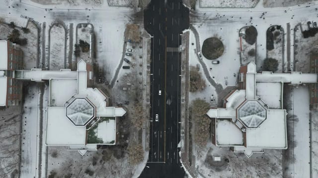 Top-down aerial view capturing the symmetrical city streets and architecture blanketed in snow during winter.