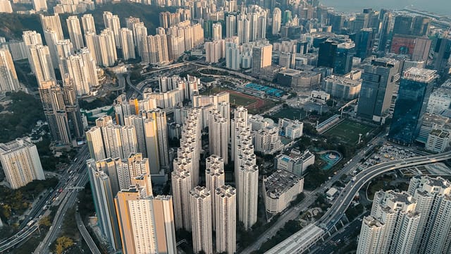 Explore the dense urban skyline of Kowloon, Hong Kong with towering skyscrapers and intricate roadways.