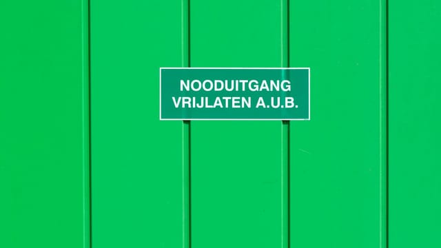 A green metal wall featuring an emergency exit sign in Dutch. Perfect for safety-themed graphics.