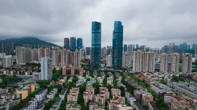 Aerial view of Shenzhen's modern skyscrapers and urban landscape under cloudy skies.