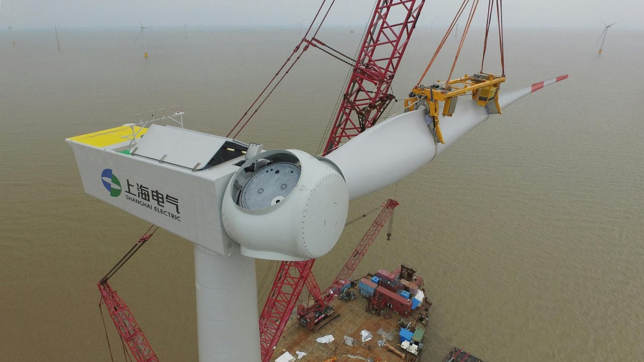 Aerial view of a wind turbine being installed over the sea, showcasing renewable energy construction.
