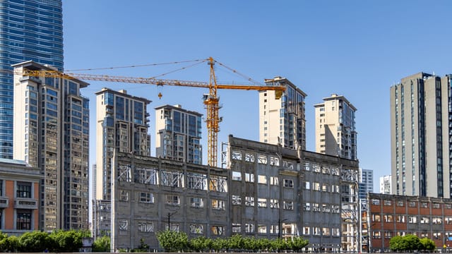 Urban redevelopment featuring cranes and high-rise buildings under a clear blue sky.