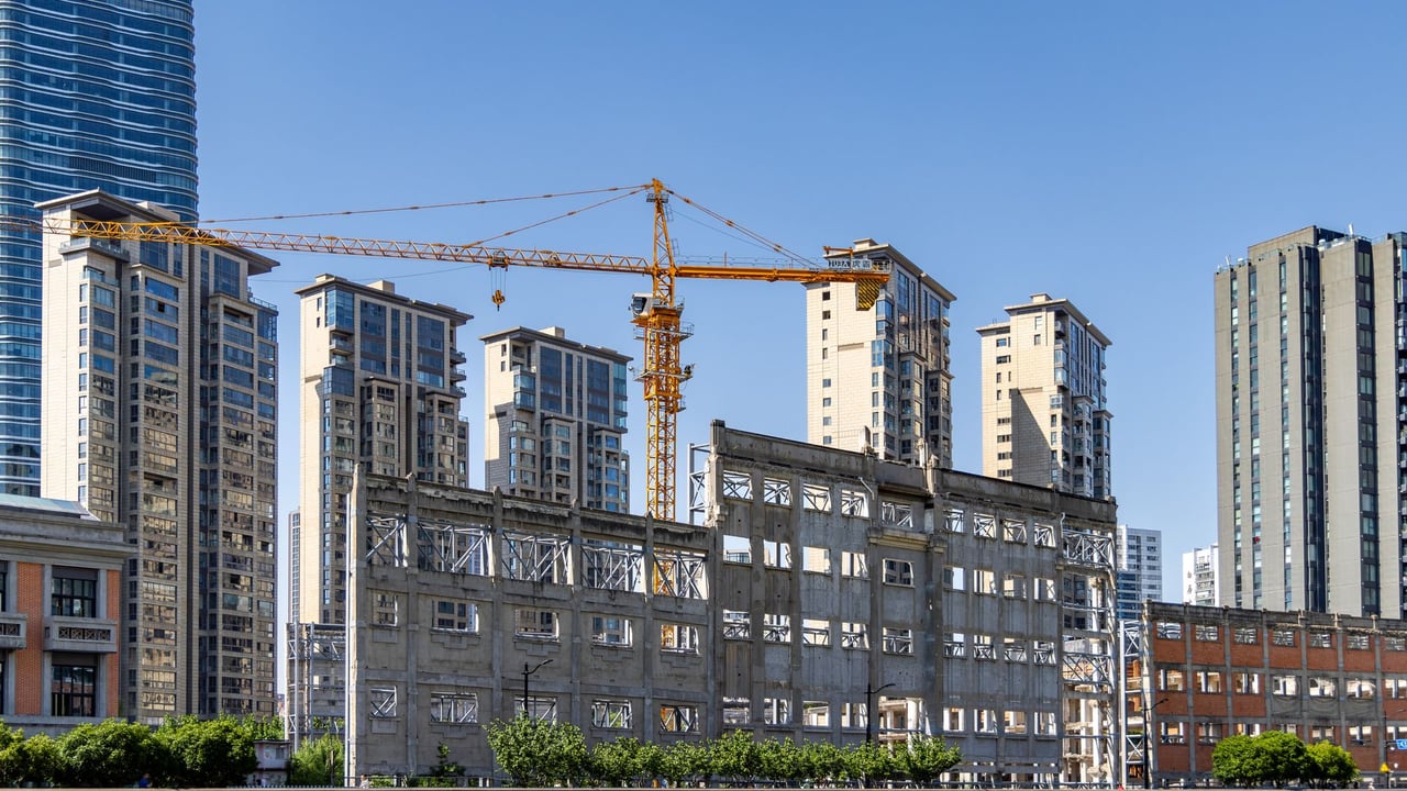 Urban redevelopment featuring cranes and high-rise buildings under a clear blue sky.