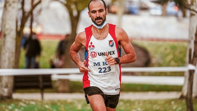 Focused male runner in a marathon race with blurred background, showcasing endurance and determination.