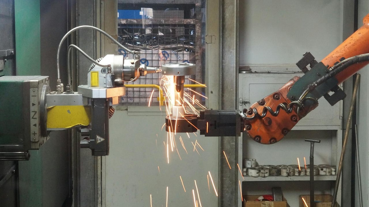 A robotic arm welding in an industrial setting, emitting bright sparks.
