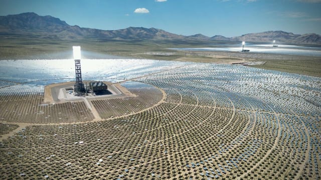 Stunning aerial view of the Ivanpah Solar Electric Generating System with mountainous backdrop.