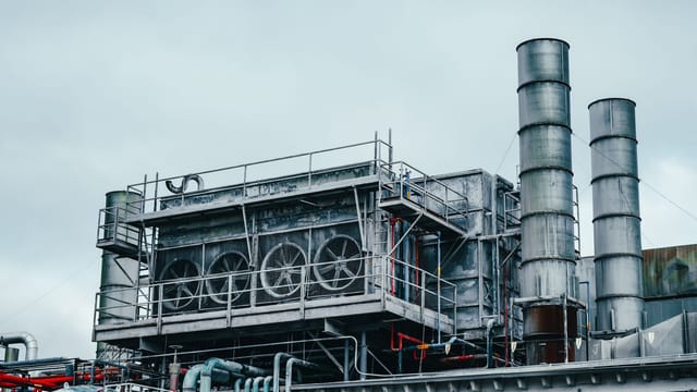 Illustrative image: Exterior view of large industrial construction with metal tubes located on factory in daytime on cloudy weather
