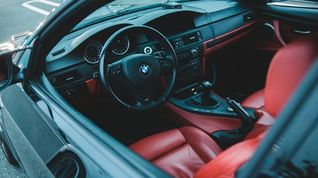 Modern comfortable interior of car with red leather seats and black stylish steering wheel on control panel