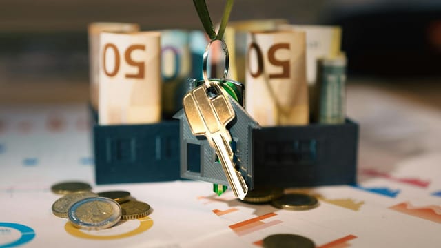 Keys hanging with money and charts, symbolizing real estate investment and financial planning.