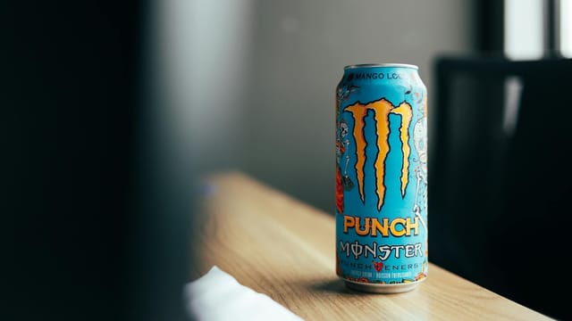 Close-up of a colorful energy drink can on a wooden table indoors.
