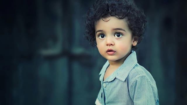 Charming portrait of a young boy with curly hair and striking eyes.