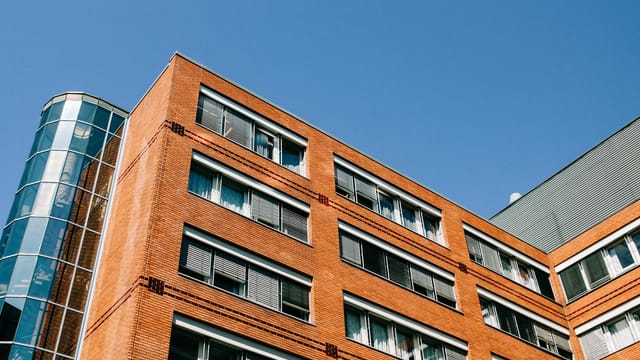 From below of contemporary high apartment building located in residential district against blue sky