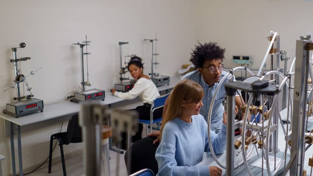Illustrative image: University students conducting physics experiments in a science laboratory, collaborating and learning in an interactive setting.