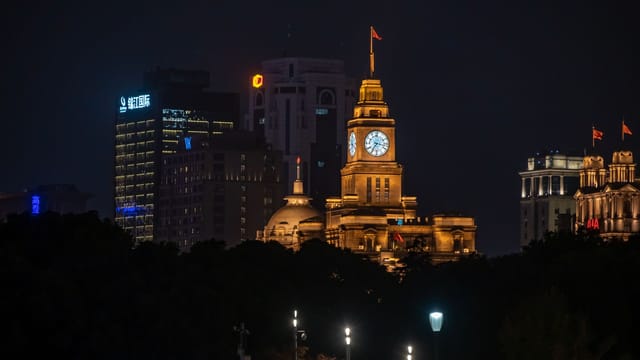 Stunning night view of The Bund skyline featuring the iconic illuminated clock tower in Shanghai, China.