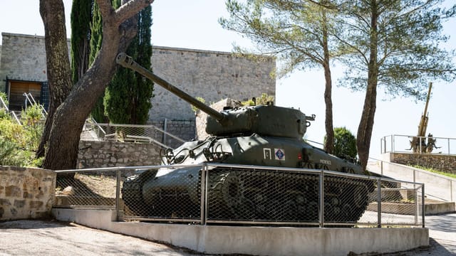 A vintage Sherman tank exhibited outdoors in Toulon, France, under bright daylight.