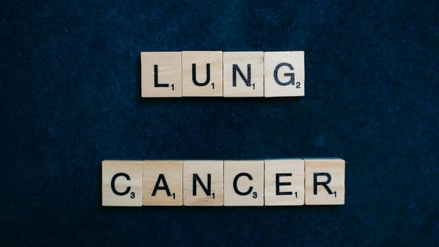 Scrabble tiles spelling lung cancer on dark background symbolizing awareness.