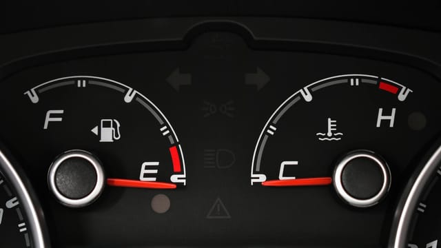 Detailed view of a car's fuel and temperature gauges on dashboard.