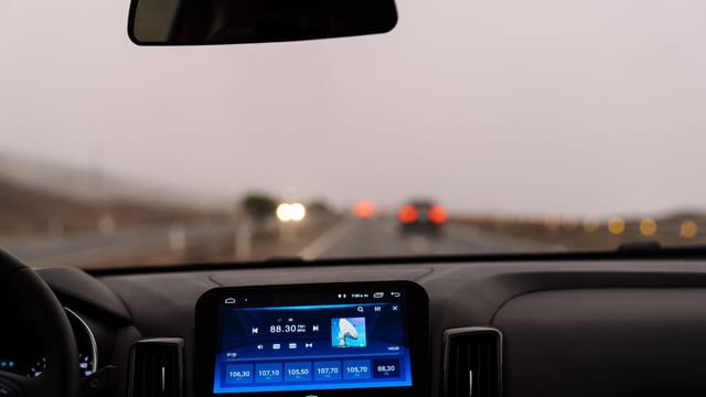 Illustrative image: Interior view of a car dashboard on an open road during the day. Perfect for travel-themed projects.