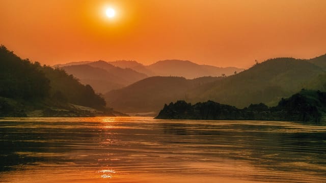 Serene sunset landscape over the Mekong River with scenic mountains in Bokeo Province, Laos.