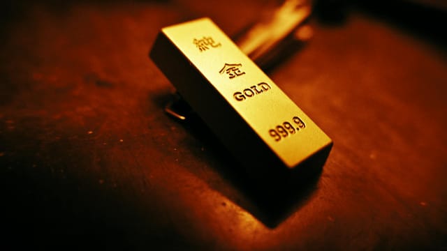 A striking close-up of a gold bar showing inscriptions, captured with warm lighting.