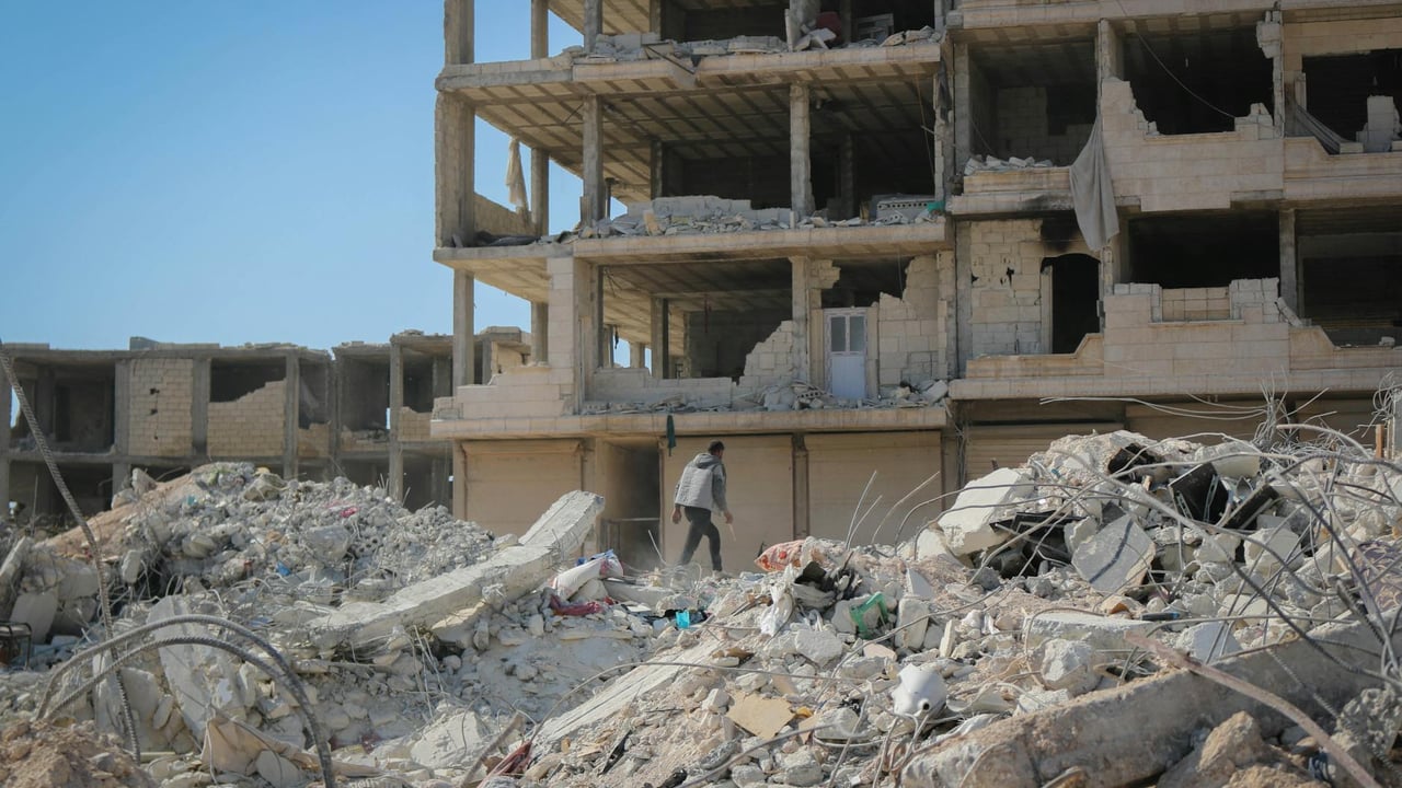 A man walks through rubble in Idlib, Syria, illustrating destruction from conflict.