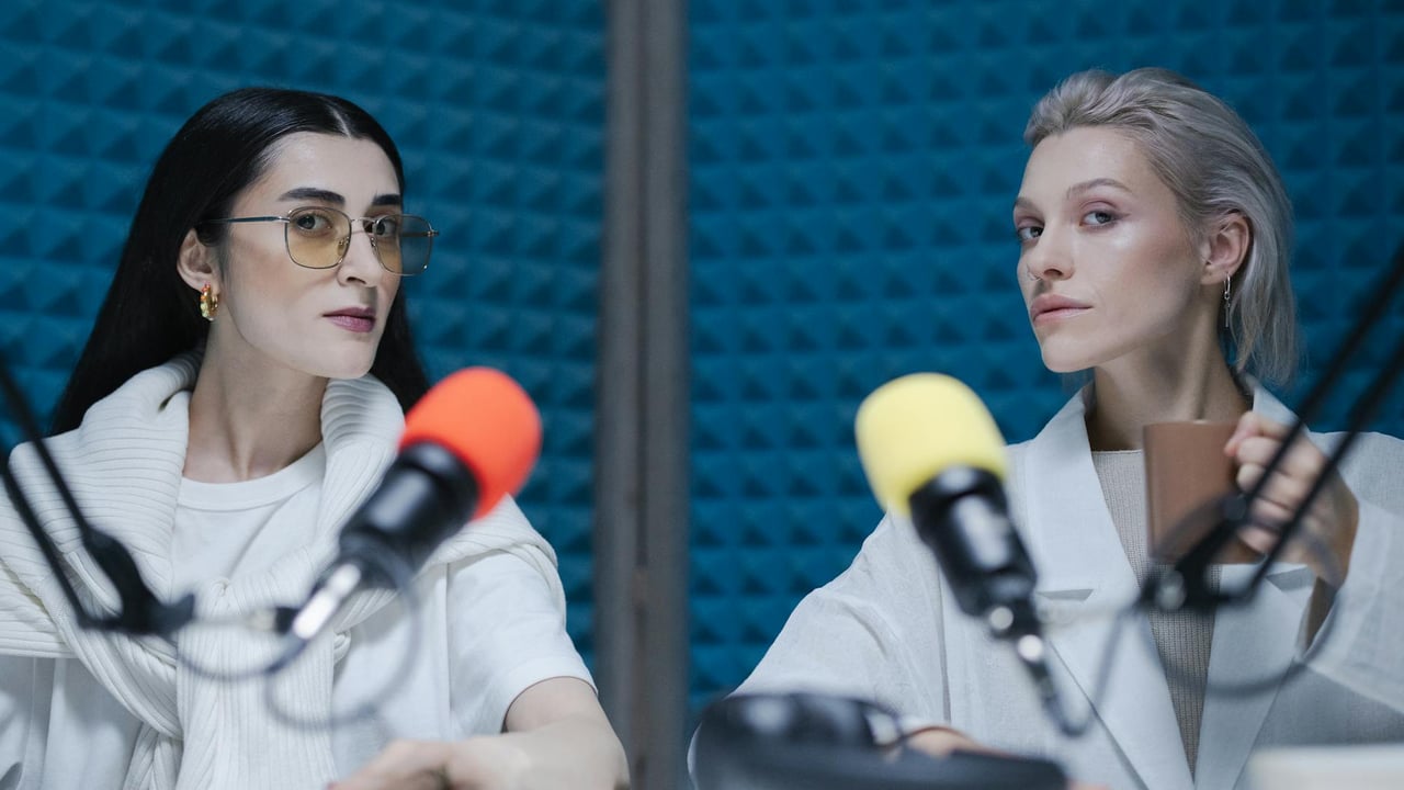 Two women in a soundproof studio with microphones, recording a podcast.