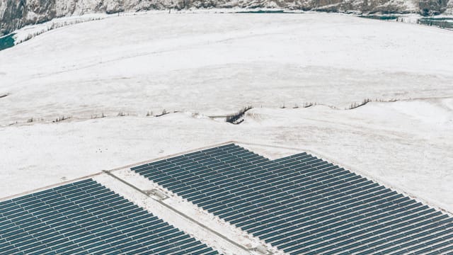 Aerial view of solar panels in a snowy winter landscape, showcasing green energy.