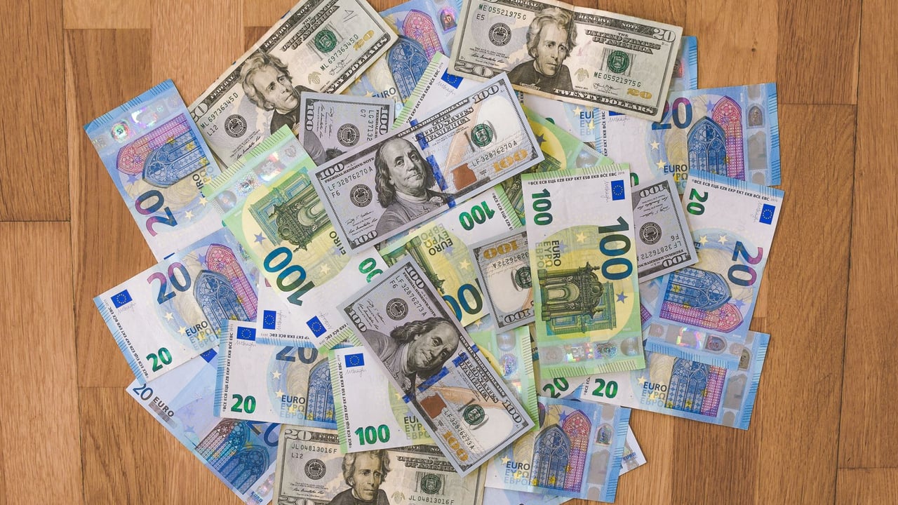 Aerial view of mixed Euro and US Dollar banknotes on a wooden floor, symbolizing global finance.