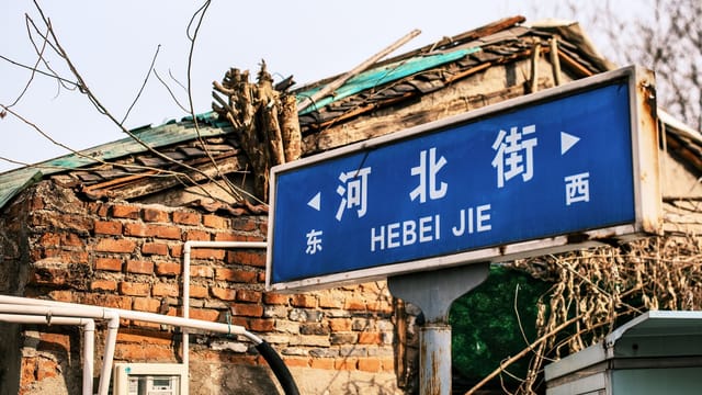 Street sign for Hebei Jie in front of rustic brick building, China.