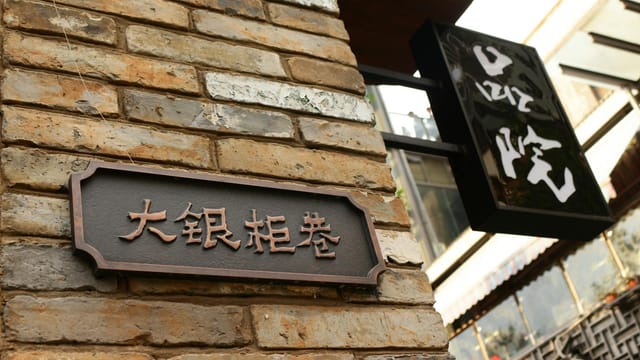 Close-up of a brick wall with traditional Chinese signs in a city environment.