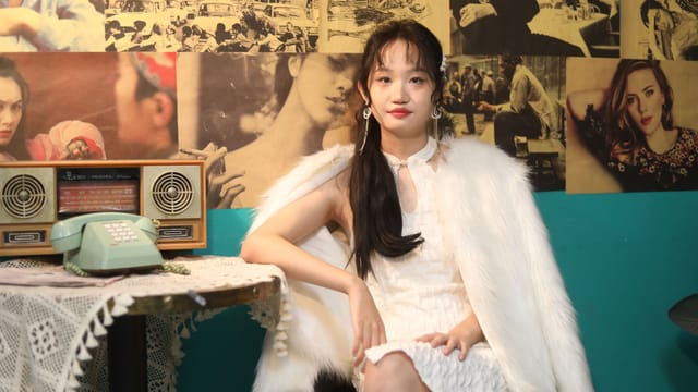 Woman in white dress and fur coat in a vintage-style cafe. Retro decor creates a nostalgic atmosphere.